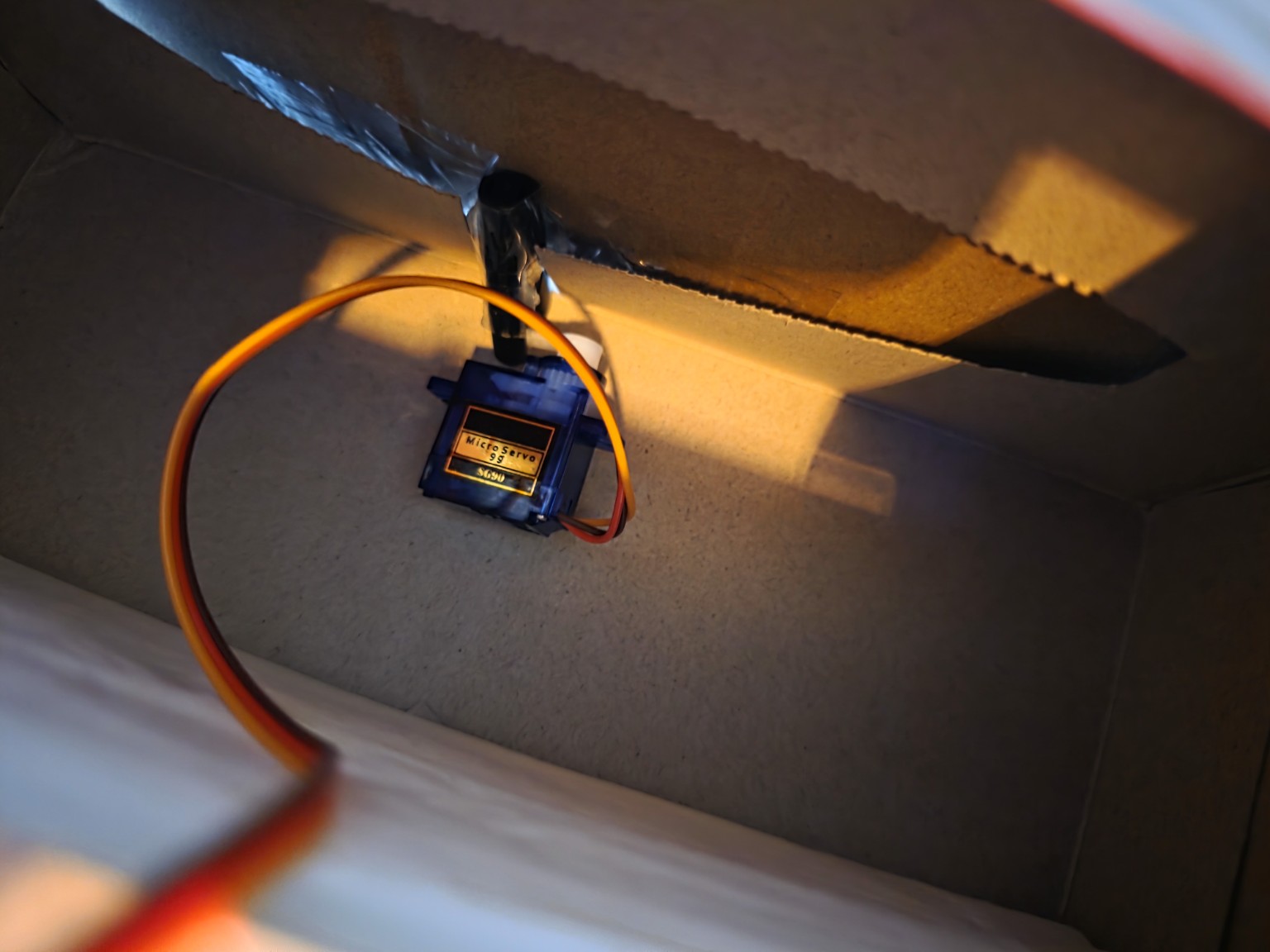 Interior view of cardboard box showing servo mounted as a latch